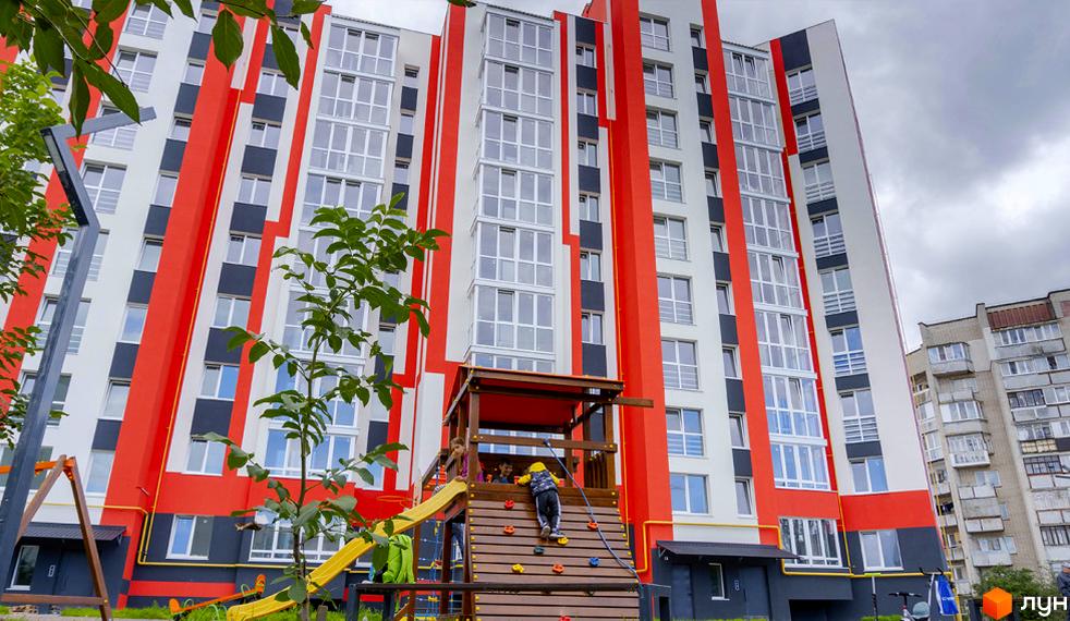 Житловий комплекс Корольова - яскрава новобудова з червоними та білими фасадами, дитячим майданчиком та зеленими зонами.