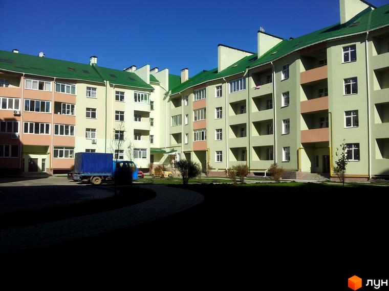 Житловий комплекс Петропавлівський: багатоповерхові будинки світло-зеленого та бежевого кольорів з зеленими дахами, розташовані навколо внутрішнього двору з газоном та доріжкою.