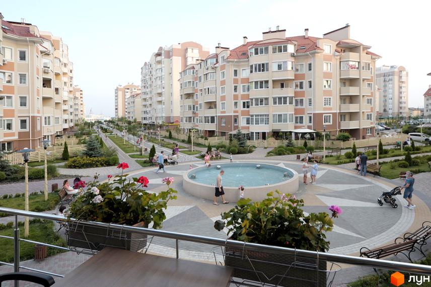 Житловий комплекс Петрівський квартал з сучасними будинками та прибудинковою територією з фонтаном і зеленими насадженнями.