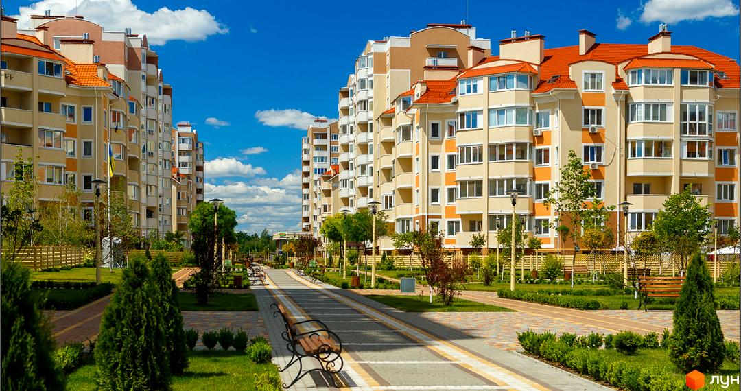 Зовнішній вигляд житлового комплексу Петрівський квартал з сучасними фасадами. Прибудинкова територія з зеленими насадженнями та доріжками.