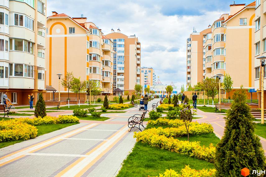 Житловий комплекс Петрівський квартал з сучасними будинками та доглянутою прибудинковою територією, озелененою газонами та доріжками.