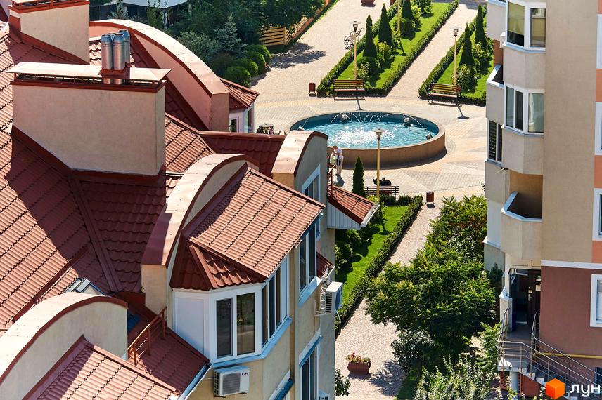 Житловий комплекс Петрівський квартал: вид на будинки з червоними черепичними дахами та прибудинкову територію з фонтаном та зеленими насадженнями.