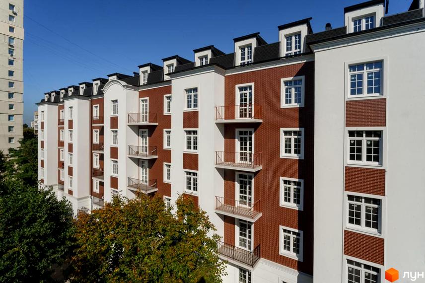 Житловий комплекс Notting Hill з червоно-білим фасадом та балконами. Навколо будинку зелені дерева.