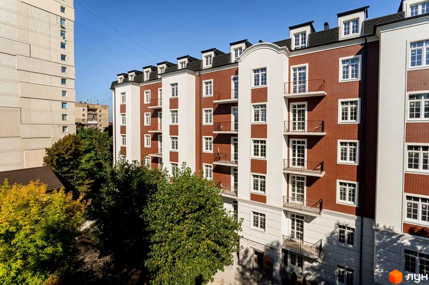 Фасад житлового комплексу Notting Hill виконаний з червоної цегли та білих елементів, з багатьма вікнами та балконами. Навколо будинку ростуть зелені дерева.