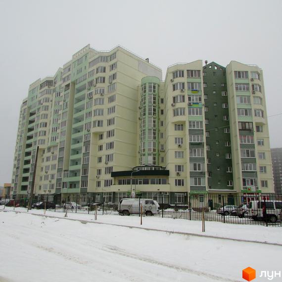 Житловий комплекс Едем з фасадом у світлих тонах та балконами. Прибудинкова територія з автомобілями та огорожею.
