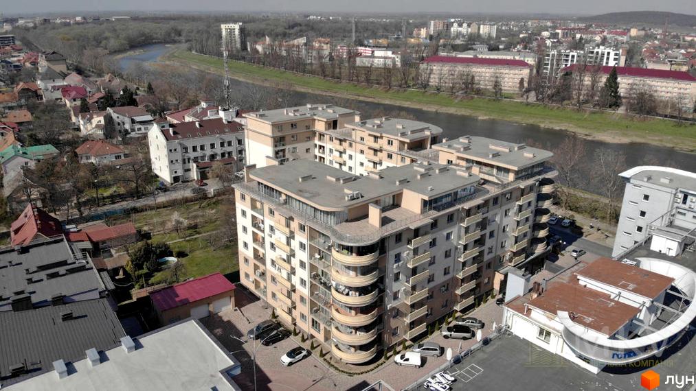 Житловий комплекс Перлина - це багатоповерховий будинок з балконами та терасами, розташований біля річки. На прибудинковій території є парковка та зелені насадження.