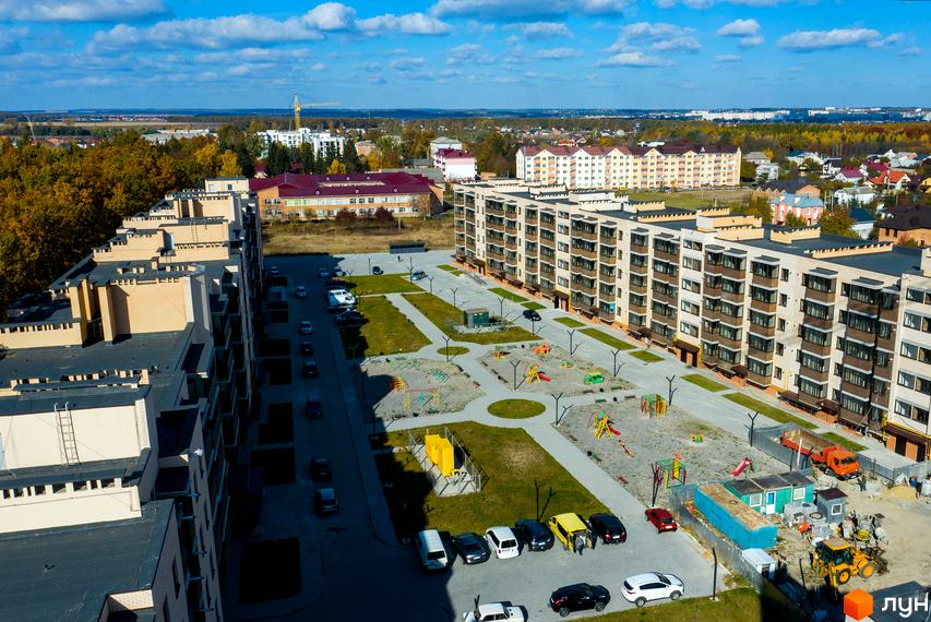 Новобудова ЖК Софія з багатоповерховими будинками та упорядкованою прибудинковою територією з дитячими майданчиками та місцями для паркування.