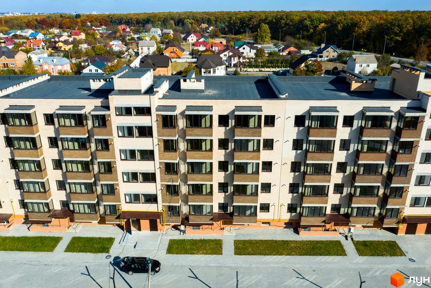 Житловий комплекс Софія: багатоповерховий будинок зі світлої цегли з численними вікнами та балконами. Навколо зелені зони та інша забудова.