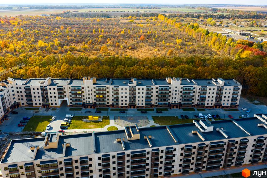 Житловий комплекс Софія - сучасна новобудова з багатоповерховими будинками та упорядкованою прибудинковою територією. Навколо комплексу зелені насадження та дерева осінніх кольорів.