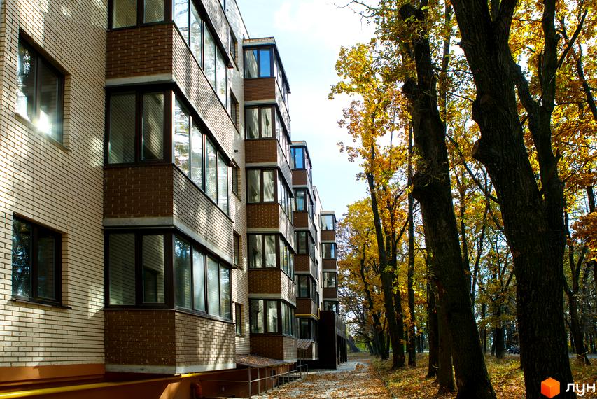 Фасад житлового комплексу Софія з цегляним оздобленням та великими вікнами. Поруч розташовані дерева з осіннім листям.
