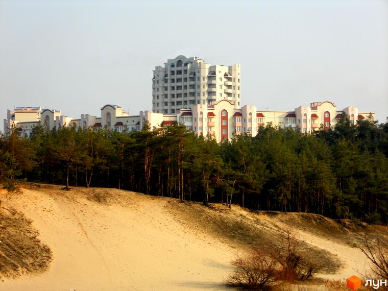 Житловий комплекс Чисті сосни з сучасними будинками на фоні лісу. Прибудинкова територія з піщаними дюнами та зеленими насадженнями.