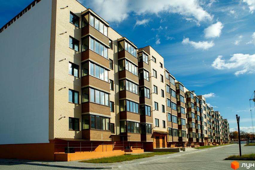 Зовнішній вигляд будинку житлового комплексу Софія з цегляним фасадом та великими вікнами. Прибудинкова територія з доглянутим газоном та бруківкою.