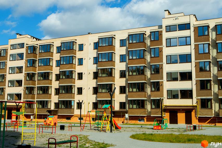 Новобудова ЖК Софія з цегляним фасадом та балконами. На прибудинковій території дитячий майданчик з гойдалками та гіркою.