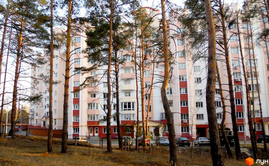 Житловий комплекс Чисті сосни з фасадом у світлих тонах, оточений соснами та прибудинковою територією.