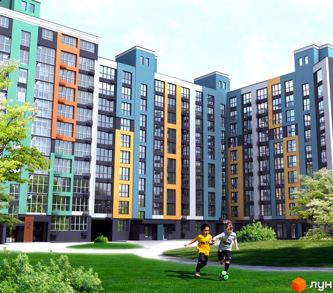 Багатоповерховий будинок з кольоровим фасадом. На прибудинковій території газон та діти грають у футбол.