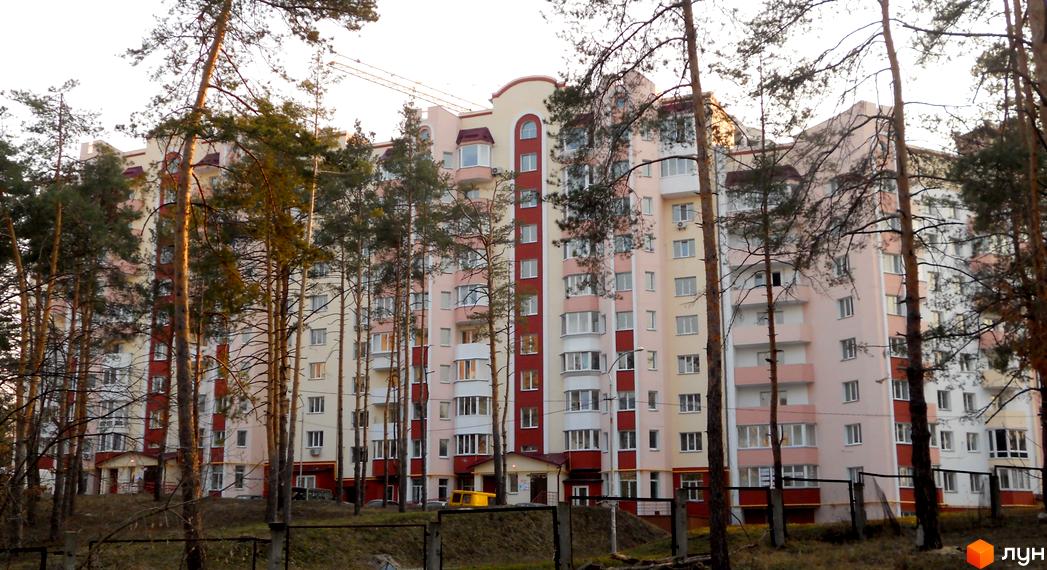 Житловий комплекс Чисті сосни з фасадом у світлих тонах, оточений соснами та зеленою територією.