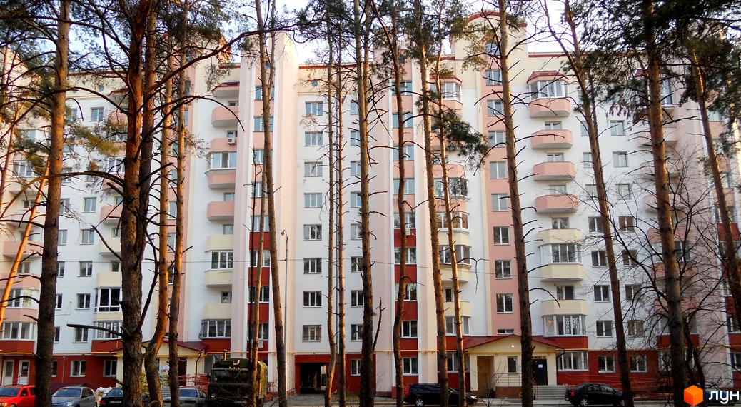 Житловий комплекс Чисті сосни з фасадом в світлих тонах, оточений соснами та прибудинковою територією.