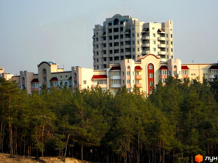 Житловий комплекс Чисті сосни з сучасною архітектурою, оточений зеленими насадженнями. Прибудинкова територія з деревами та природою.