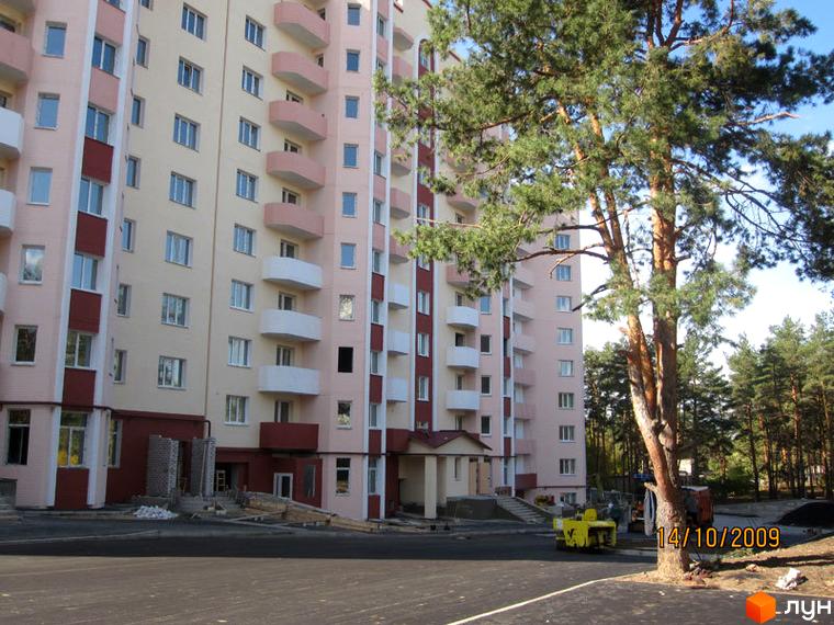 Житловий комплекс Чисті сосни з фасадом світлого кольору та балконами. Прибудинкова територія з зеленими насадженнями та автомобільною стоянкою.