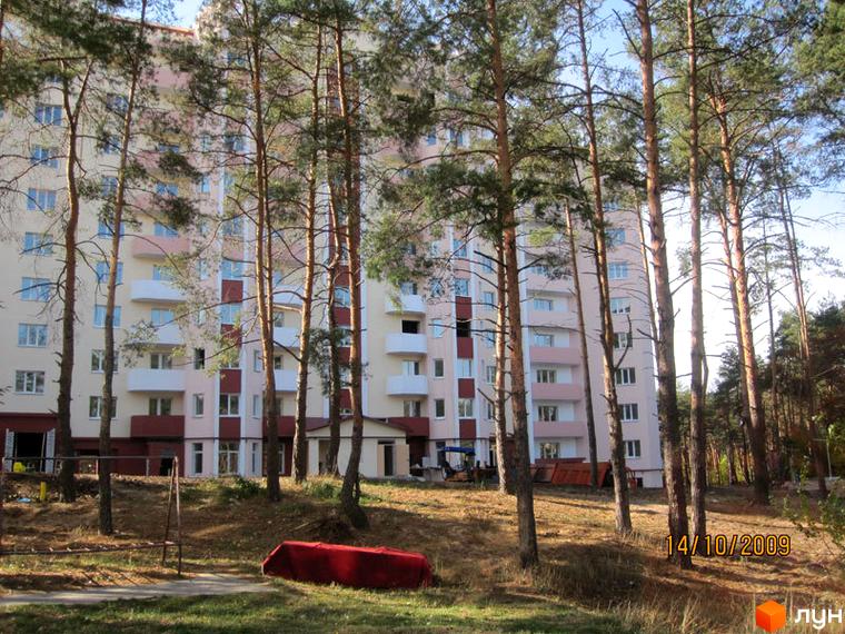 Житловий комплекс Чисті сосни з фасадом у світлих тонах, оточений соснами та прибудинковою територією.