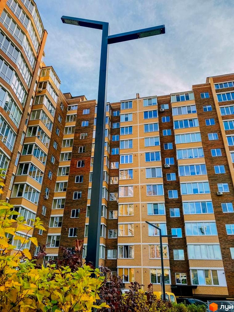 Житловий комплекс Преміум Парк – цегляні фасади будівель з великою кількістю вікон та засклених балконів. Навколо комплексу зелені насадження та сучасне освітлення.