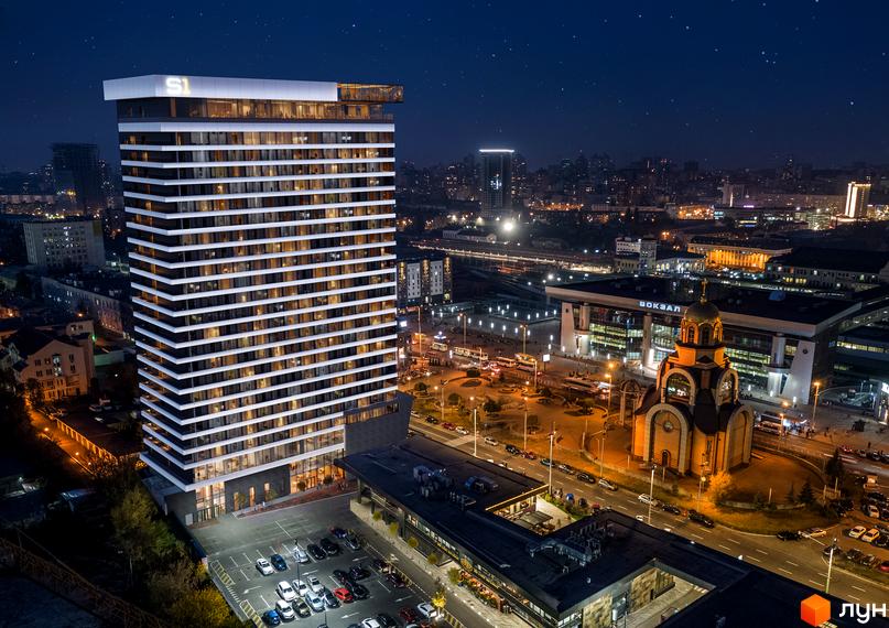 Апарт-комплекс Standard One Terminal - це висотна новобудова з панорамними вікнами та підсвічуванням у вечірній час. Навколо комплексу розташована парковка та міська інфраструктура.