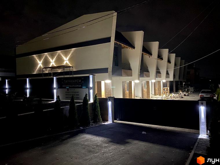 Таунхауси Royal life – сучасні будинки з підсвічуванням фасаду та доглянутою прибудинковою територією вночі.