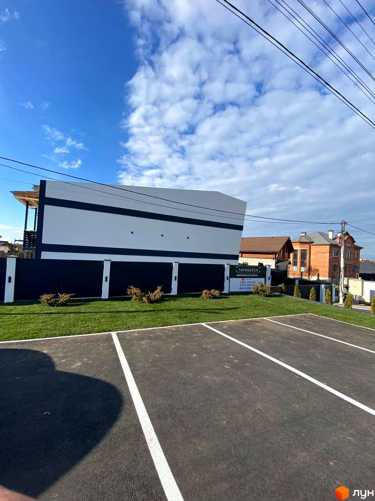 Зовнішній вигляд житлового комплексу Таунхауси Royal life з парковкою та доглянутою прибудинковою територією. Сучасна архітектура та зелені насадження.