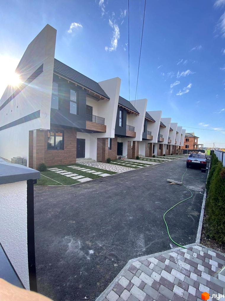 Таунхауси Royal life - це сучасні двоповерхові будинки з оригінальною архітектурою та доглянутою прибудинковою територією. На фото представлений ряд будинків з акуратними газонами та вимощеними доріжками.