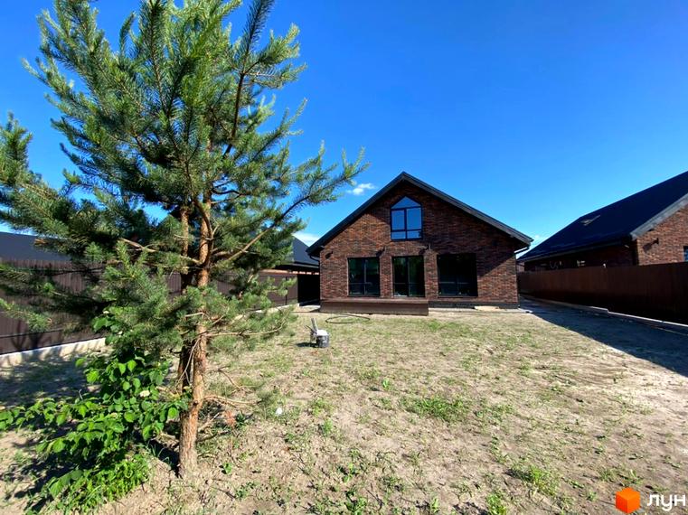 Котеджне містечко КМ Одноповерховий Київ - Гореничі. Цегляний будинок з великими вікнами та зеленою прибудинковою територією під блакитним небом.