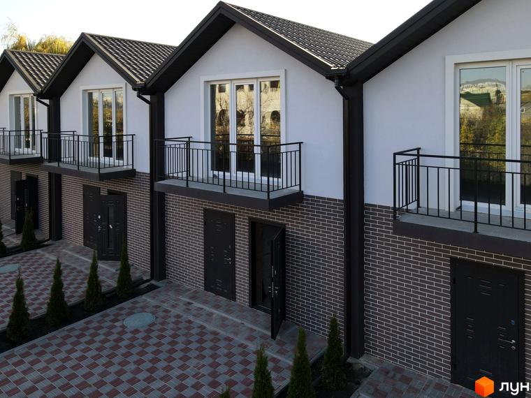 Таунхаус на Інститутській: фасади будинків з цегляною обробкою та балконами, упорядкована прибудинкова територія з бруківкою та туями.