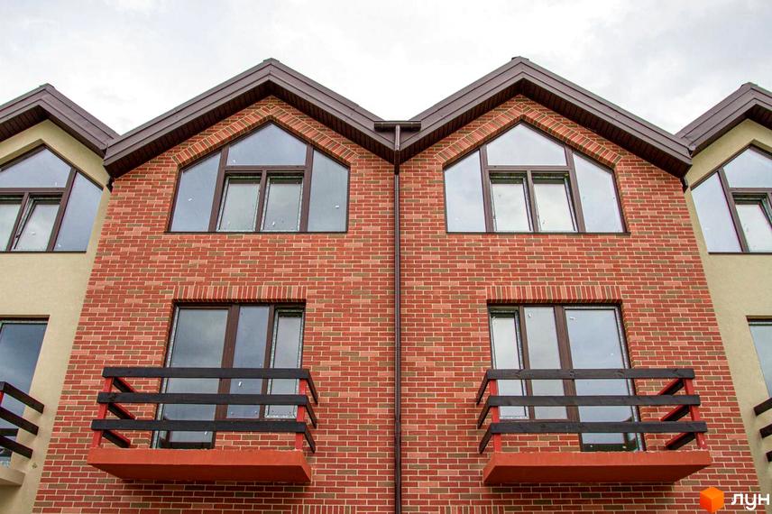 Фасад двоповерхового цегляного будинку з балконами та великими вікнами в таунхаусах Modern House.