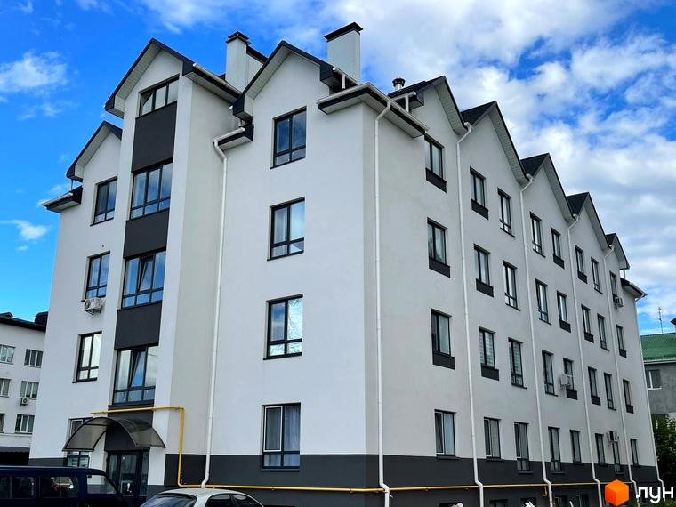 Зовнішній вигляд житлового комплексу Затишний на вулиці Січова, 31. Будинок має біло-сірий фасад та чорний дах.