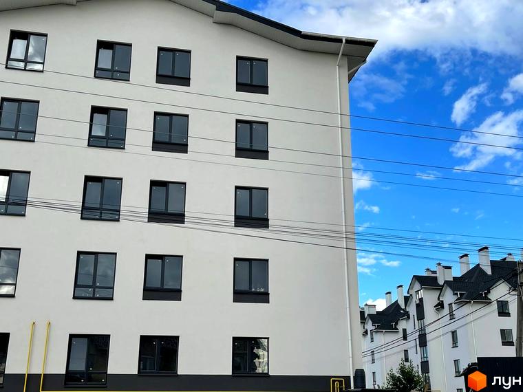 Зовнішній вигляд новобудови ЖК Затишний з численними вікнами. На задньому плані видно інші будинки комплексу.