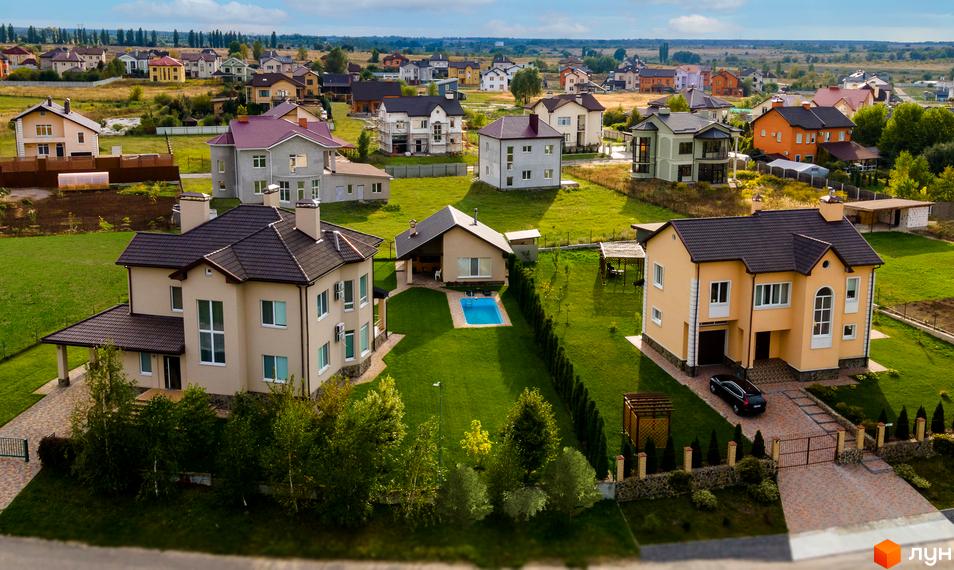 Котеджне містечко Home Resort: двоповерхові будинки з коричневими дахами, зелені газони та басейн. На території комплексу розташовані сучасні будинки та доглянута прибудинкова територія.