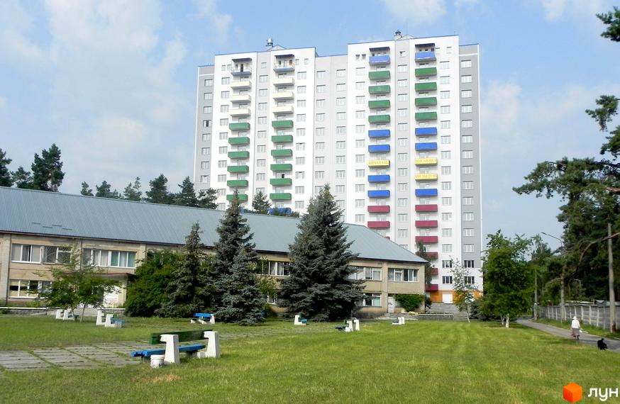 Вид на житловий комплекс Райдужний з багатоповерховим будинком та прибудинковою територією з зеленими насадженнями.