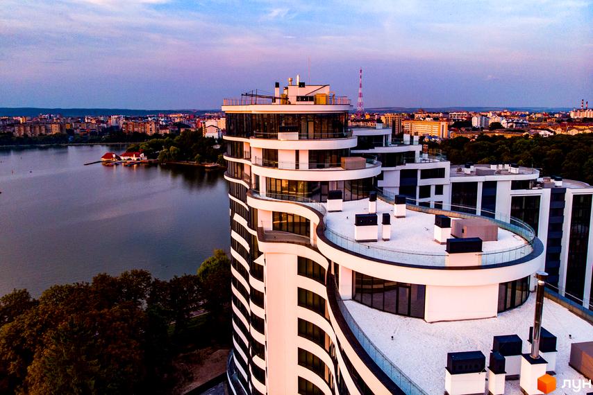 Зображення Житлового комплексу Parus з видом на озеро та місто. Багатоповерхова будівля з білими балконами та панорамними вікнами.