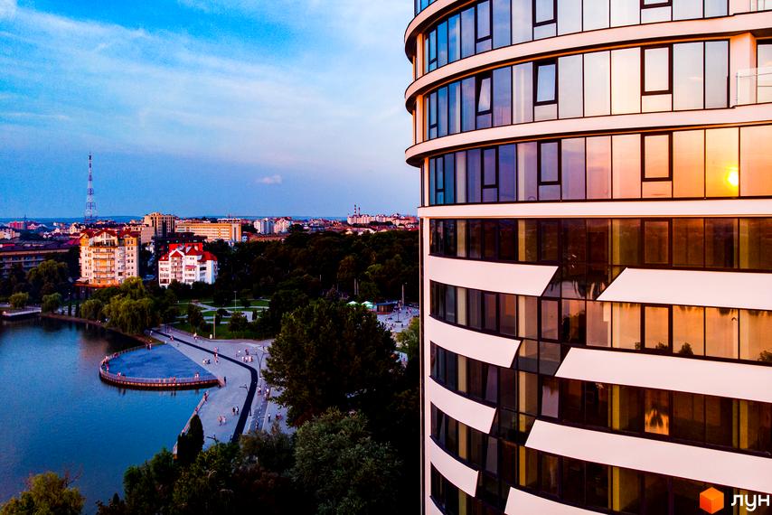 Зображення Житлового комплексу Parus з видом на озеро та місто. Багатоповерхова будівля з панорамними вікнами.