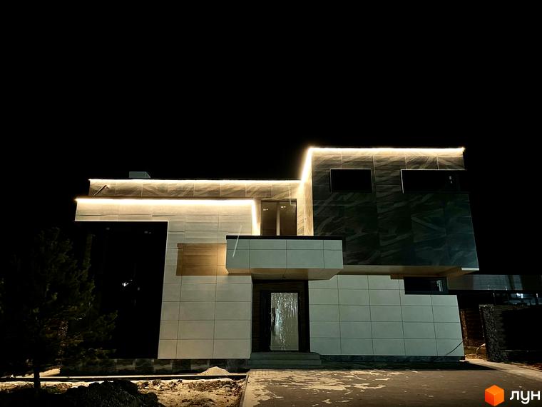 Зображення будинку в ЖК КМ Crystal Forest вночі. Фасад будинку з світлодіодним підсвічуванням. На передньому плані асфальтована доріжка.