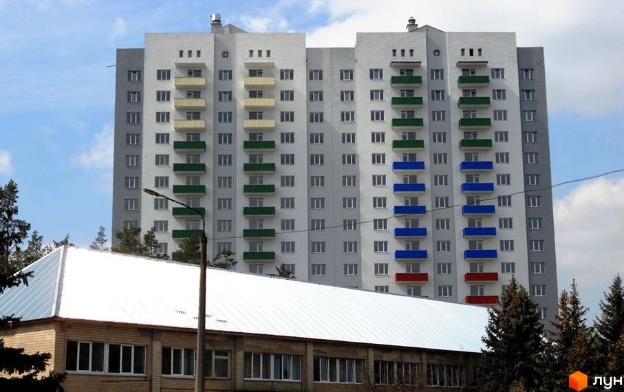 Житловий комплекс Райдужний з яскравими балконами та прибудинковою територією, оточений зеленими насадженнями.