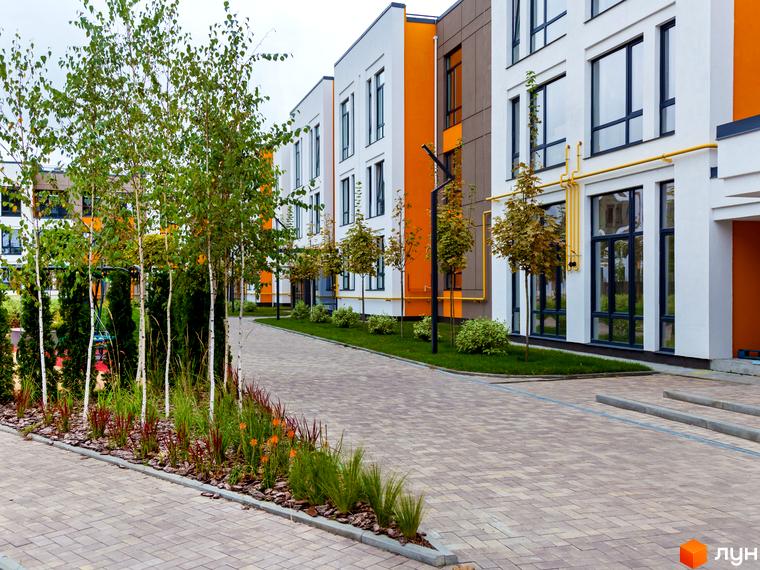 Вигляд фасаду та прибудинкової території Житлового комплексу Найкращий квартал. Малоповерхові будинки з великими вікнами, озеленення.