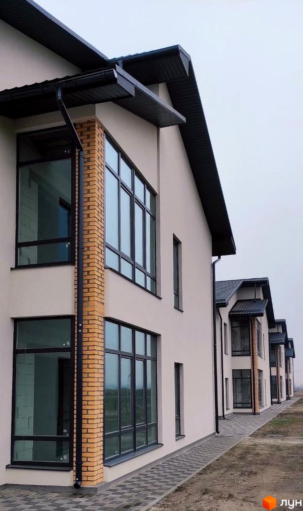Фасад будинку Житловий комплекс Лелека з панорамними вікнами та цегляною колоною. Вимощена доріжка з бруківки перед будинком.