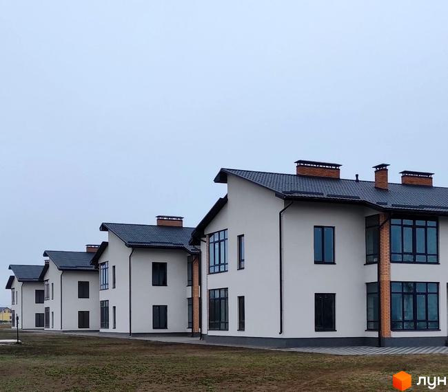 Зовнішній вигляд будинків ЖК Лелека з сірими дахами та білими стінами, розташованих на доглянутій прибудинковій території.
