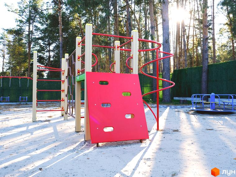 Дитячий майданчик з ігровим комплексом, червоною стіною для лазіння та каруселлю на території Таунхауси Green Heaven.