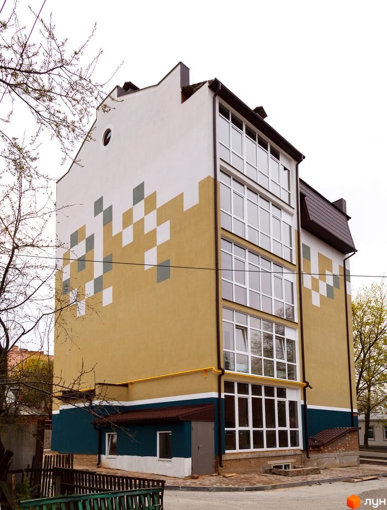 Фасад будинку на вулиці Коржівська, 54, з геометричним візерунком та великими вікнами. Поруч видно паркан та дерева.