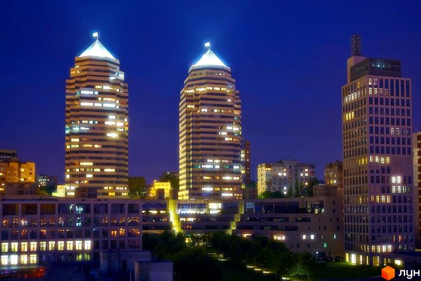 Житловий комплекс Амфітеатр вночі з освітленими фасадами. Прибудинкова територія з зеленими насадженнями та освітленням.