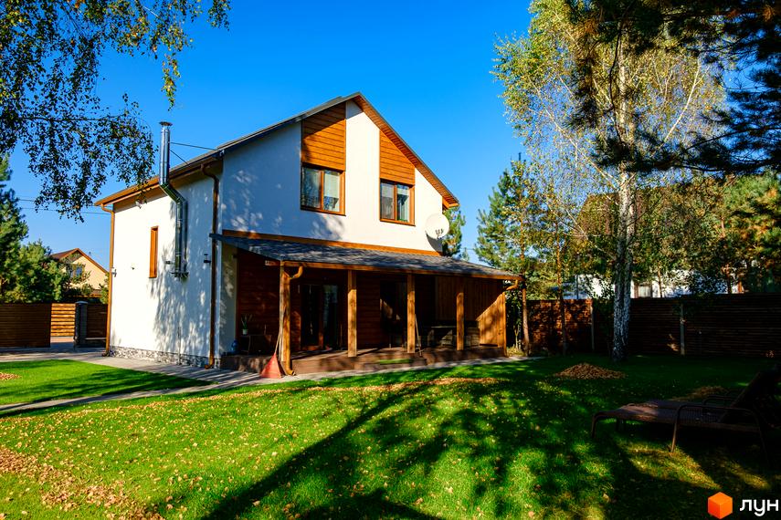 Котеджне містечко Калина-2: двоповерховий будинок з терасою та ганком, зелена галявина з деревами та лежаками.