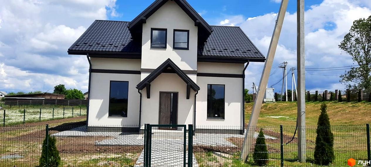 Білий двоповерховий будинок з темним дахом та вікнами. Перед будинком зелений газон та огорожа, викладена доріжка до входу.