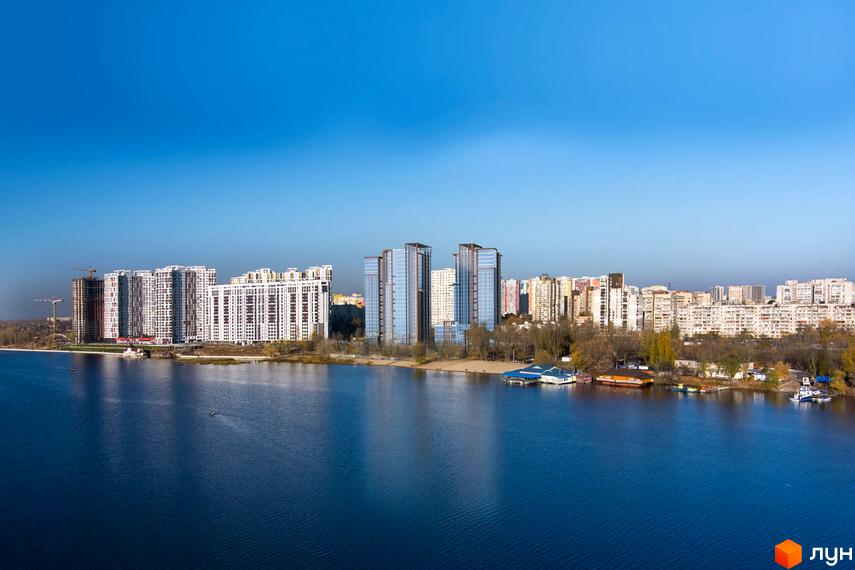 Панорамне фото Житлового комплексу Нова Слобідка на березі річки. Видно багатоповерхові будинки та зелену прибережну зону.