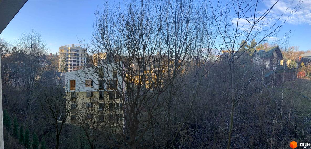 Зовнішній вигляд новобудови на вул. Ярославенка, 23а, оточеної деревами в зимовий період. Навколо будинку видно прибудинкову територію з деревами та сусідніми будівлями.